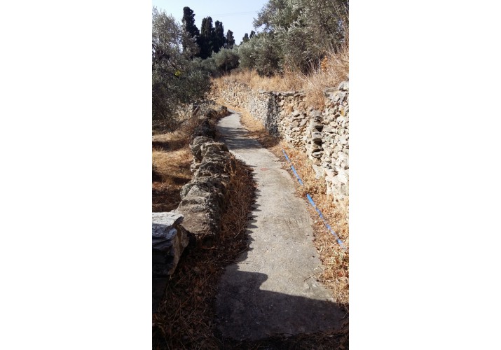 Κατά μήκος του δρόμου υψώνονται τοίχοι από ξερολιθιά, που συγκρατούν το χώμα και οριοθετούν τα κτήματα