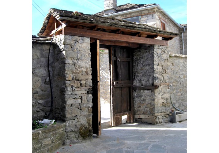 Χαρακτηριστική αυλόπορτα με δίριχτη στέγη σε μαντρότοιχο