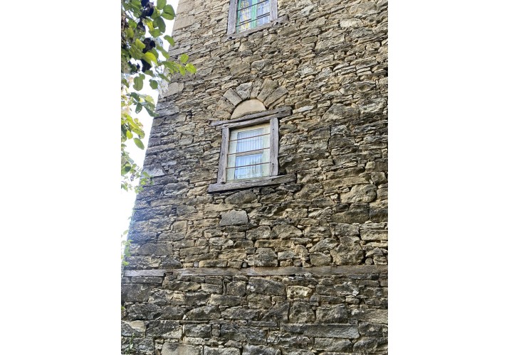 Μικρό παράθυρο με ξύλινο τετράφυλλο με σιδερένιες οριζόντιες βέργες  και ανακουφιστικό τόξο λίθινο 