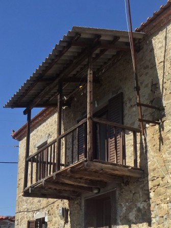 Παραδοσιακό μπαλκόνι με ξύλινες δοκούς και στέγαση με λαμαρίνα